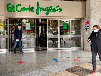 Dos personas pasan por delante de la entrada de un centro comercial de El Corte Inglés, en Valencia.