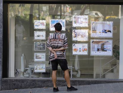 Un joven mira anuncios de alquiler de una inmobiliaria en Barcelona.