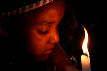 Un niño sostiene una vela durante una ceremonia de bautismo dentro de la capilla del quilombo Kalunga, en la culminación de la semana de peregrinación y celebración de la patrona Nossa Senhora de Abadia, en Cavalcante (Brasil), el lunes.