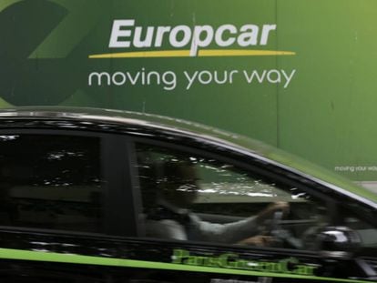 Un conductor pasa junto a un cartel de Europcar en Par&iacute;s.
