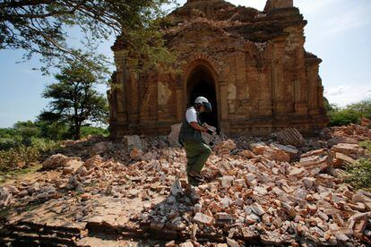 Un fotógrafo camina entre los escombros de una pagoda.