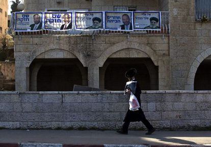 Un joven ultraortodoxo pasa ante una casa decorada con carteles del partido religioso sefard&iacute; Shas, en Jerusal&eacute;n. 
