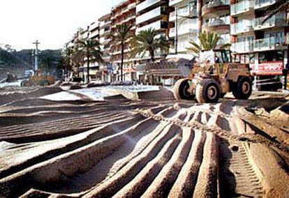 Una excavadora retira la arena en el paseo marítimo de Lloret de Mar.