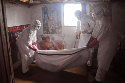 Trabajadores sanitarios retiran el cadáver de un muerto de ébola en una casa de las afueras de Monrovia (Liberia).
