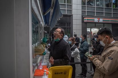 Un hombre se somete a un test de covid mientras otras personas aguardan en una cola, este sábado en Pekín. 