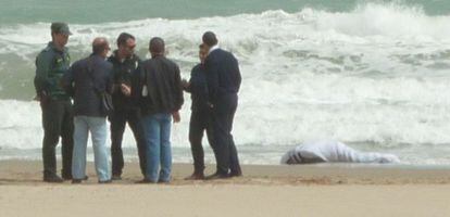 Agentes de la Guardia Civil y vecinos junto al cad&aacute;ver hallado en la playa de la Zenia de Orihuela. 