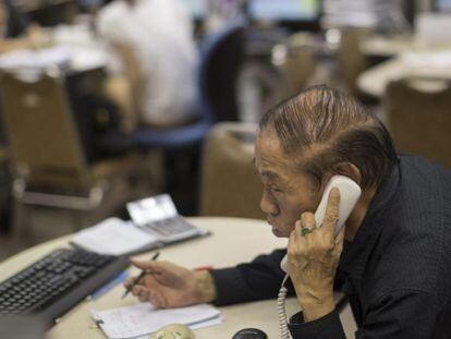 Un agente de bolsa habla por teléfono en una correduría en Hong Kong.