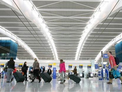 Varios pasajeros se dirigen con los equipajes a los mostradores de facturación en la nueva terminal del aeropuerto londinense de Heathrow.