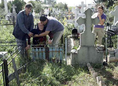 La familia de Marian Milita, en Targoviste. Arriba, sus hermanas sostienen a la madre, Elvira, en el cementerio del pueblo donde quieren enterrarlo, bajo la mirada de Izabela, la hija de Marian. Abajo, en la casa familiar.