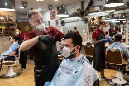 Un peluquero corta el pelo a un cliente en la barbería Bearbero de La Latina.