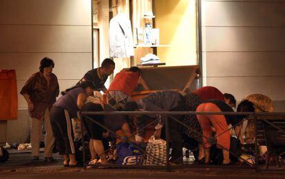 Un grupo de personas busca alimentos en la basura a las puertas de un centro comercial en Madrid. 