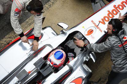 Los mecánicos de McLaren preparan el monoplaza del británico Jenson Button para el entrenamiento.