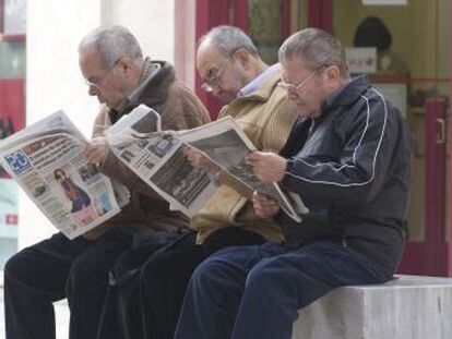 Un grupo de jubilados lee la prensa en una calle de Málaga. jubilados