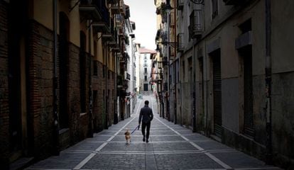 Una persona pasea a su perro por una calle desierta del casco histórico de Pamplona.