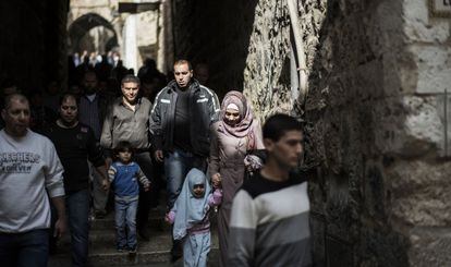 Fieles palestinos caminan junto a soldados armados en la Ciudad Vieja de Jerusalén, el viernes