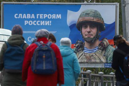 Un grupo de gente, este miércoles en San Petesburgo delante de una valla publicitaria con un soldado ruso.