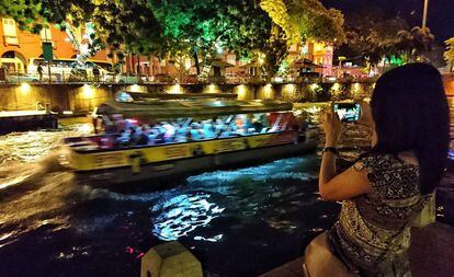 Una turista fotografiando un crucero fluvial en Malaca (Malasia).