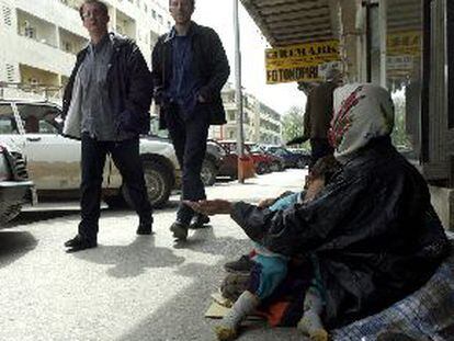 Una indigente gitana con su hijo en los brazos pide dinero a unos viandantes, ayer en Pogdorica.