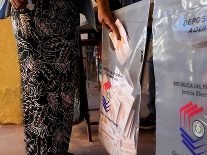 Una mujer deposita su voto en una urna en un colegio electoral en la ciudad de Mariano Roque Alonso, este domingo.