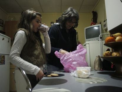 La ni&ntilde;a portuguesa Matilde Alexandra Alves bebe un vaso de leche mientras su madre Maria Alexandra Gomez saca de la bolsa la comida dada por el ayuntamiento de Elvas (Portugal).