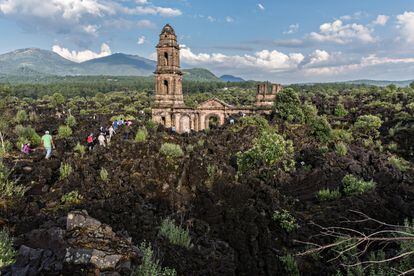 Varios turistas pasean alrededor de  San Juan Parangaricutiro, enterrado por la lava.