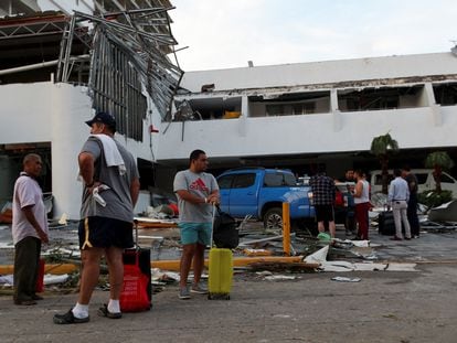 Un grupo de personas espera junto un edificio destruido por el paso del huracán 'Otis', en Acapulco, este 26 de octubre.