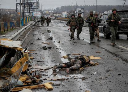 Miembros del Ejército ucranio caminan cerca del cuerpo de un soldado ruso en Bucha, a las afueras de Kiev.