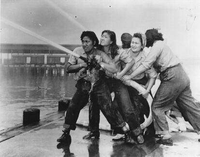 Varias mujeres tratan de sofocar un incendio provocado durante el bombardeo japonés a la base naval de Pearl Harbour.