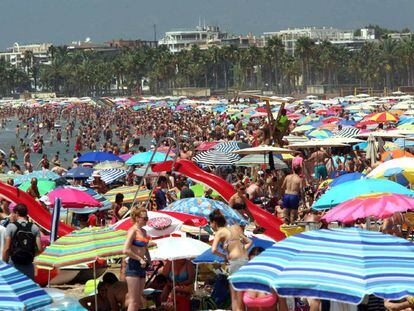 Imagen de una playa repleta de turistas al inicio de las vacaciones. 