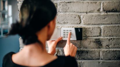 Una mujer marca el número de seguridad en un sistema de alarma.