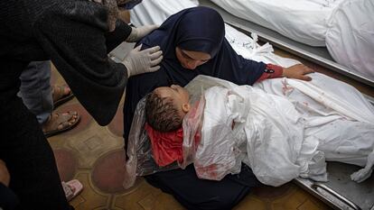 Una mujer sostenía a su hijo mientras extendía la mano para tocar el cuerpo de su marido, ambos muertos en un bombardeo del ejército israelí en la franja de Gaza, en el hospital de Jan Yunis, el martes.