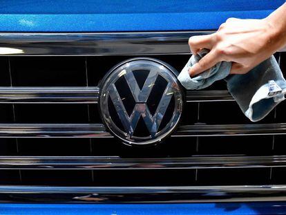 A staff member cleans the logo of a SUV VW Touareg on display ahead of the annual general meeting of German carmaker Volkswagen, in Berlin on May 3, 2018. / AFP PHOTO / Tobias SCHWARZ