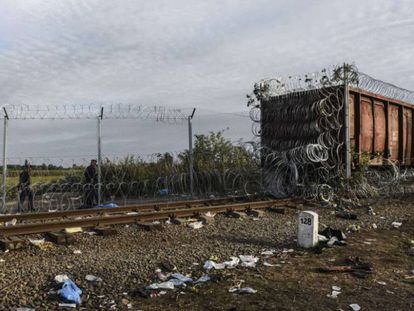 La policía húngara camina al lado de un vagón de ferrocarril cubierto de alambre en la frontera de Hungría con Serbia.