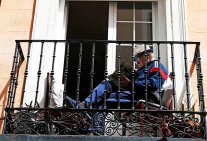 Un hombre lee en un balcón, el Primero de Mayo en Madrid.