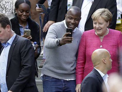 Angela Merkel posa con un visitante en el d&iacute;a de puertas abiertas de la canciller&iacute;a en Berl&iacute;n.