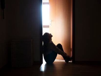 Una adolescente, sentada en el pasillo de su casa.