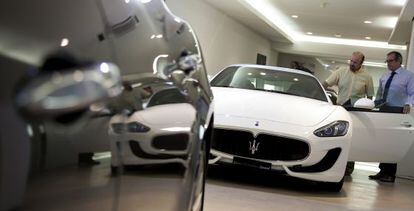 Un vendedor (izquierda) muestra un Maserati a un posible comprador en un concesionario.