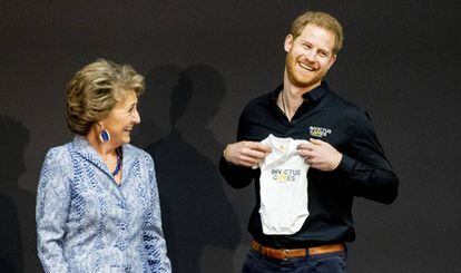 El príncipe Enrique, al lado de la princesa Margarita de Holanda, con el 'body' que recibió para su hijo en La Haya.