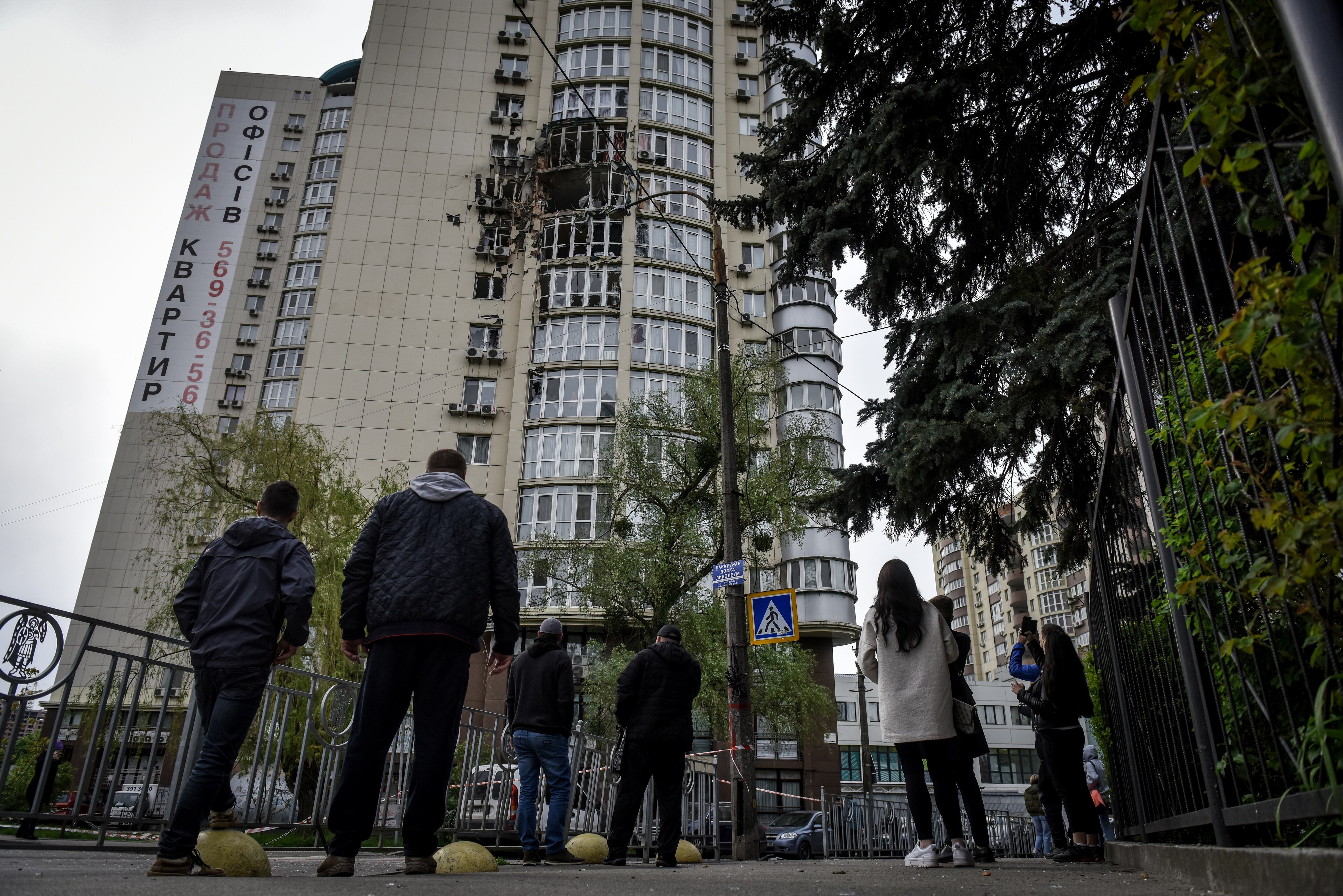 Un grupo de personas observa este lunes un apartamento en Kiev dañado por un dron ruso.
