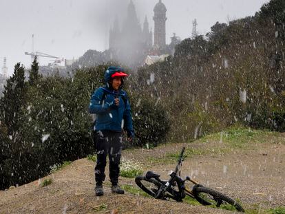 Un ciclista descansa mientras nieva en Collserola. Al fondo , el Tibidabo.