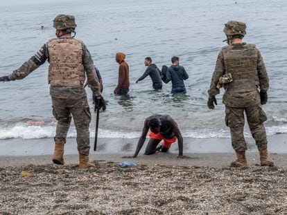 Soldados españoles junto a inmigrantes que han cruzado a nado por la frontera del Tarajal, en Ceuta, este martes.