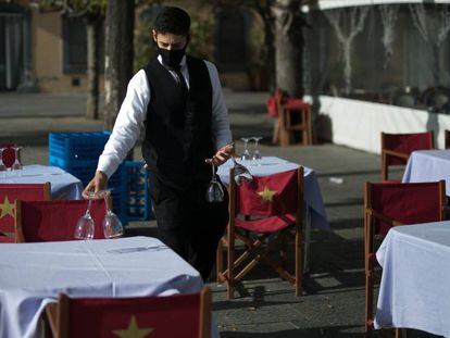 Un cambrer prepara les taules de la terrassa d'un restaurant de Barcelona, al gener.