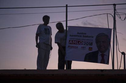 Dos hombres cuelgan un cartel de López Obrador.