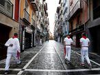 7 de julio. San Fermín. Tres corredores del encierro caminan por la calle Estafeta 7 de julio, vacía de gente el día grande de las fiestas en Pamplona, que ha arrancado de manera atípica sin encierro. Debido a la pandemia se han suspendido los festejos.