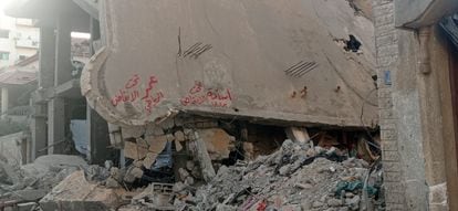 Escombros de un edificio tras un bombardeo con el mensaje rotulado en rojo: “Osama Badawi sigue bajo los escombros”.