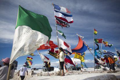Una aficionada ondea una bandera con varias enseñas nacionales en el recorrido de la séptima etapa del Dakar.