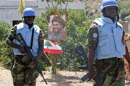 Dos <i>cascos azules</i> pasan ante un cartel del líder de Hezbolá, Hasan Nasralá, en Yater, al sur de Líbano, el miércoles 23 de agosto.