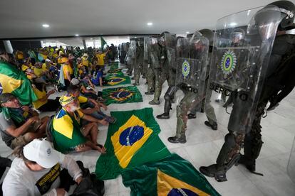 Bolsonaristas sentados frente a la policía luego de invadir el Palacio de Planalto.