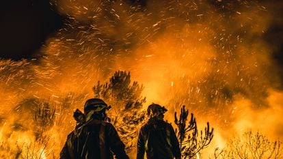 Dos bomberos, ante el fuego declarado en Boiro (A Coruña).