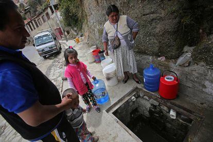 Una familia llena sus envases de agua en un barrio de La Paz.